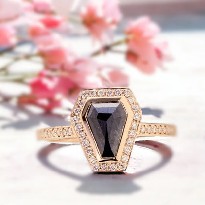 Black Salt and Pepper Coffin Diamond Ring with Halo Setting featuring a natural coffin-cut black salt and pepper diamond surrounded by a halo of round accent diamonds, set on a white metal pavé band with a gothic-inspired statement ring design and prominent prong setting.