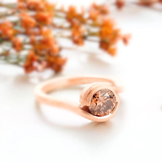 Brown Diamond Ring Fairtrade Rose Gold Wave Cognac Diamond Ring showing a rose gold wave-style bypass ring with a round-cut brown diamond in a sculptural handcrafted design