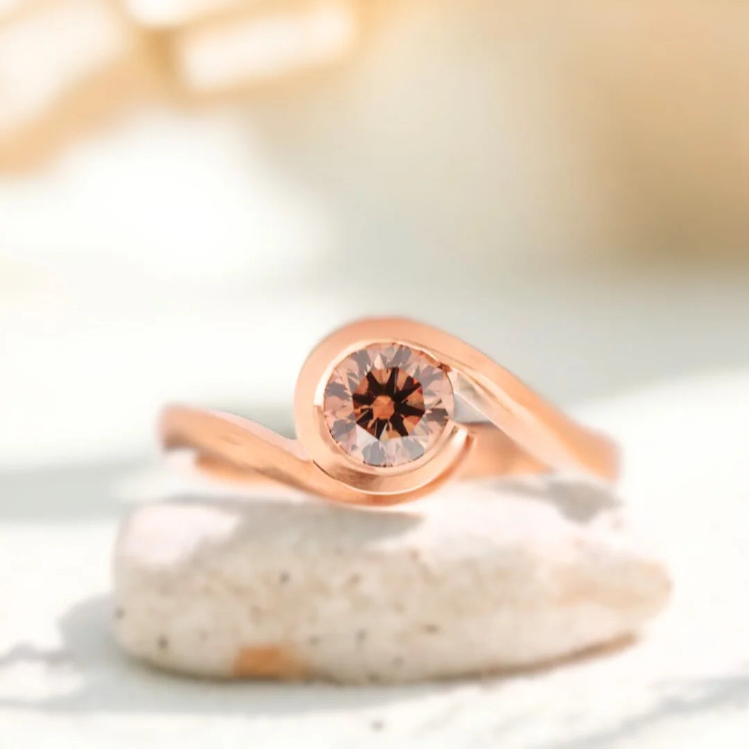 Brown Diamond Ring Fairtrade Rose Gold Wave Cognac Diamond Ring showing a rose gold wave-style bypass ring with a round-cut brown diamond in a sculptural handcrafted design