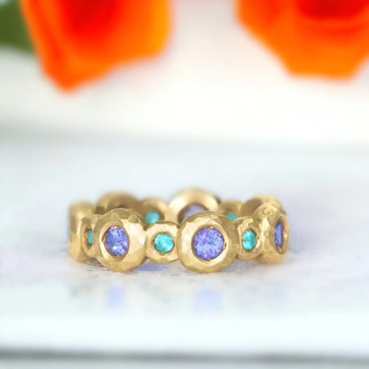 Eternity Band Ring Tourmaline and Tanzanite Gold Eternity Band Ring featuring round-cut natural blue and ocean-inspired gemstones set in a continuous eternity band with a sleek gold straight shank design.