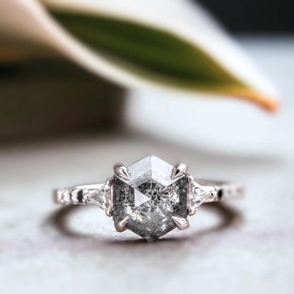 Hexagon Salt and Pepper Diamond Ring with Geometric Diamond Design featuring a hexagon-cut salt-and-pepper diamond center stone, round side diamonds, geometric setting, flair shank band, and modern engagement ring style.
