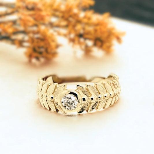 Leaf-inspired White Diamond Engagement Ring Marquise Bezel Diamond Ring featuring a round-cut white diamond set in a gold-tone band with leaf-patterned detailing, wide tapered structure, and clean bezel style influence