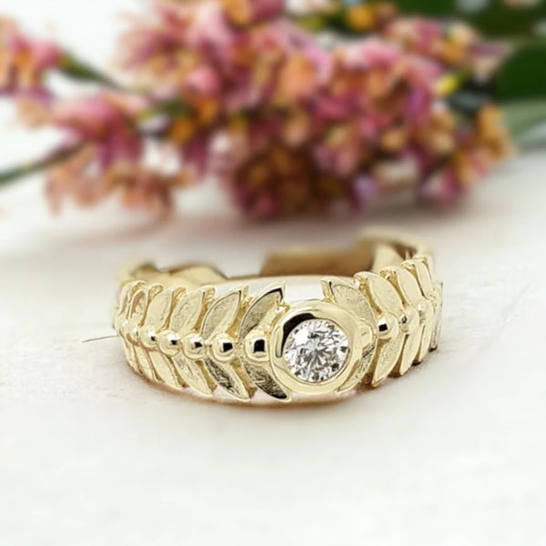 Leaf-inspired White Diamond Engagement Ring Marquise Bezel Diamond Ring featuring a round-cut white diamond set in a gold-tone band with leaf-patterned detailing, wide tapered structure, and clean bezel style influence