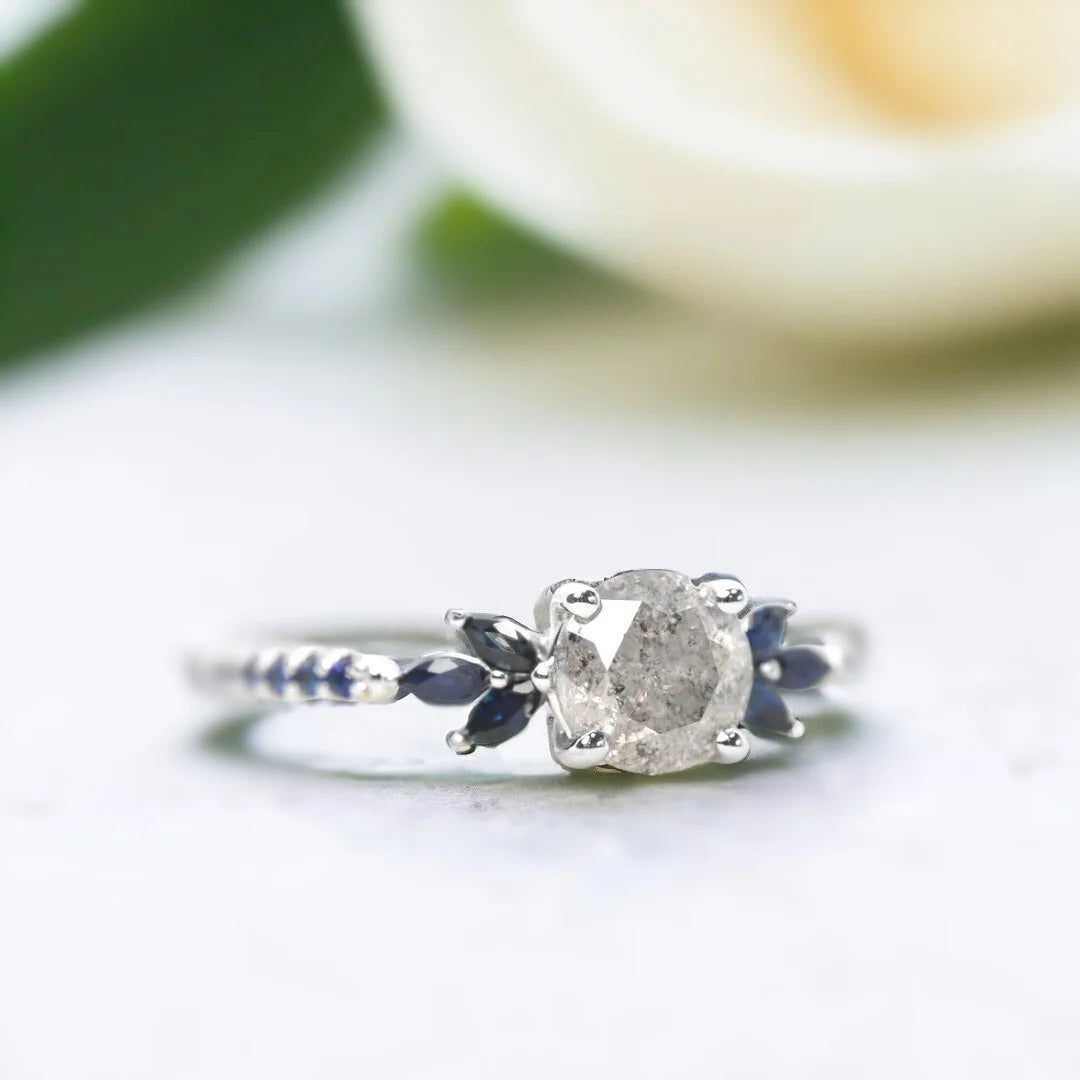 Milky Way Diamond Ring Mossy Glen Engagement Ring Statement Ring featuring a round salt-and-pepper diamond center stone with soft milky grey tones, accented by blue marquise and round gemstones in a slim modern engagement ring design