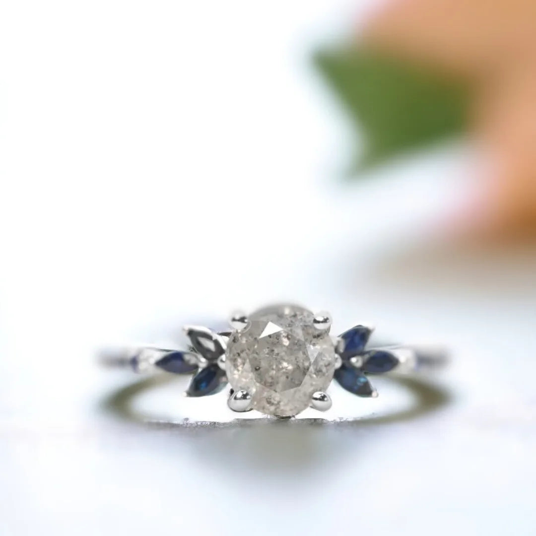 Milky Way Diamond Ring Mossy Glen Engagement Ring Statement Ring featuring a round salt-and-pepper diamond center stone with soft milky grey tones, accented by blue marquise and round gemstones in a slim modern engagement ring design