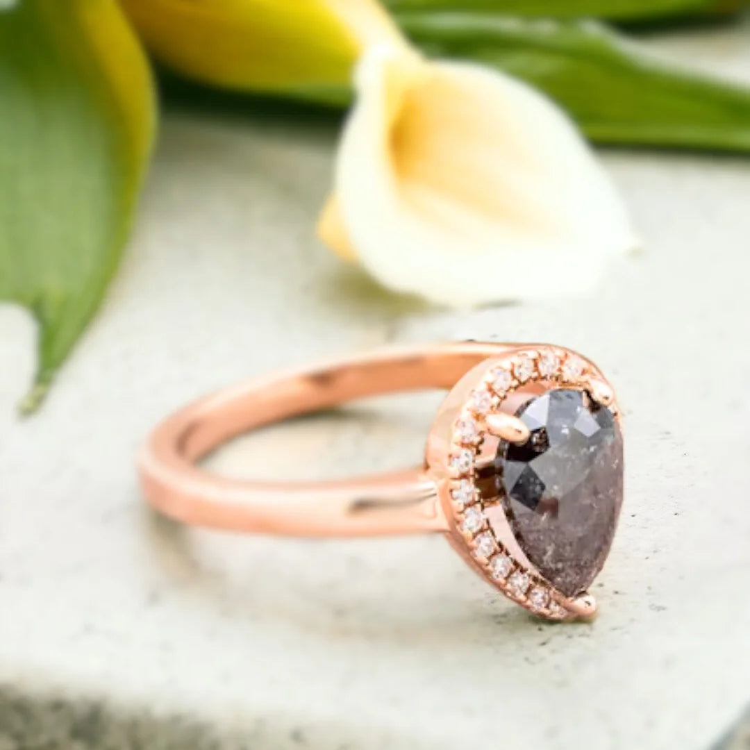 Natural Salt and Pepper Diamond Ring With Pear Cut Pavé Engagement Style showcasing a pear-cut natural salt and pepper diamond center stone with organic inclusions, surrounded by round pavé diamond accents on a straight shank engagement style band, crafted in white gold, rose gold and platinum options with a modern, elegant handcrafted finish and fine jewelry appeal.