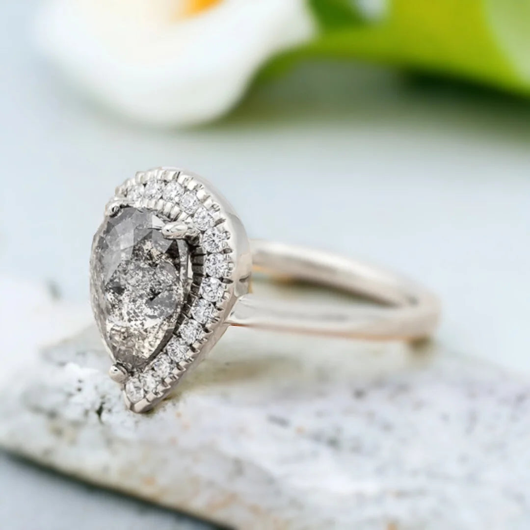Natural Salt and Pepper Diamond Ring with Pear-Cut Pavé Accents featuring a pear-cut natural salt and pepper diamond center stone with delicate pavé round diamond accents on a straight shank diamond engagement ring with an elegant handcrafted design.
