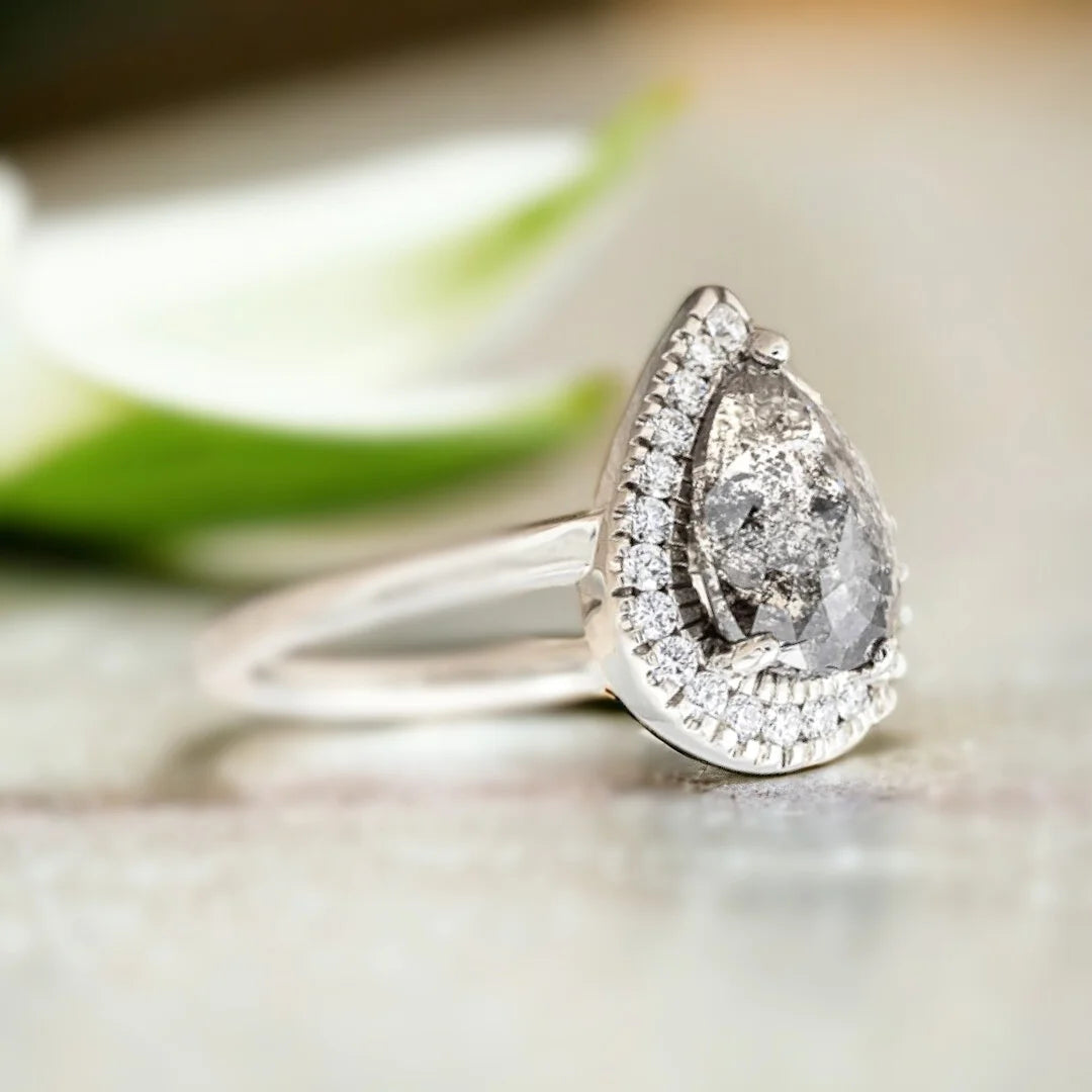 Natural Salt and Pepper Diamond Ring with Pear-Cut Pavé Accents featuring a pear-cut natural salt and pepper diamond center stone with delicate pavé round diamond accents on a straight shank diamond engagement ring with an elegant handcrafted design.
