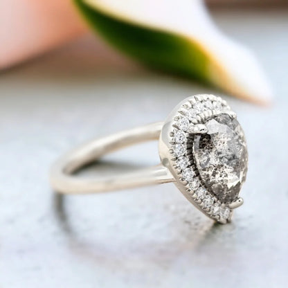 Natural Salt and Pepper Diamond Ring with Pear-Cut Pavé Accents featuring a pear-cut natural salt and pepper diamond center stone with delicate pavé round diamond accents on a straight shank diamond engagement ring with an elegant handcrafted design.