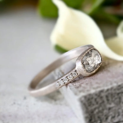 Natural Salt and Pepper Diamond Ring East-West Cushion Floating Bezel featuring a rose cushion-cut salt-and-pepper diamond in an east-west floating bezel setting with a straight shank and round diamond side stones.