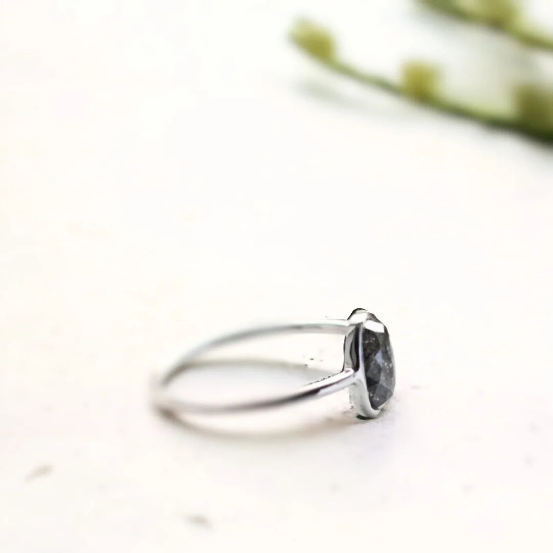 Oval Salt And Pepper Diamond Bezel Ring In White Gold featuring a 1.17 CT rose oval cut salt and pepper diamond in a white gold bezel setting with a minimalist engagement ring design and straight shank band.