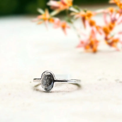 Oval Salt And Pepper Diamond Bezel Ring In White Gold featuring a 1.17 CT rose oval cut salt and pepper diamond in a white gold bezel setting with a minimalist engagement ring design and straight shank band.