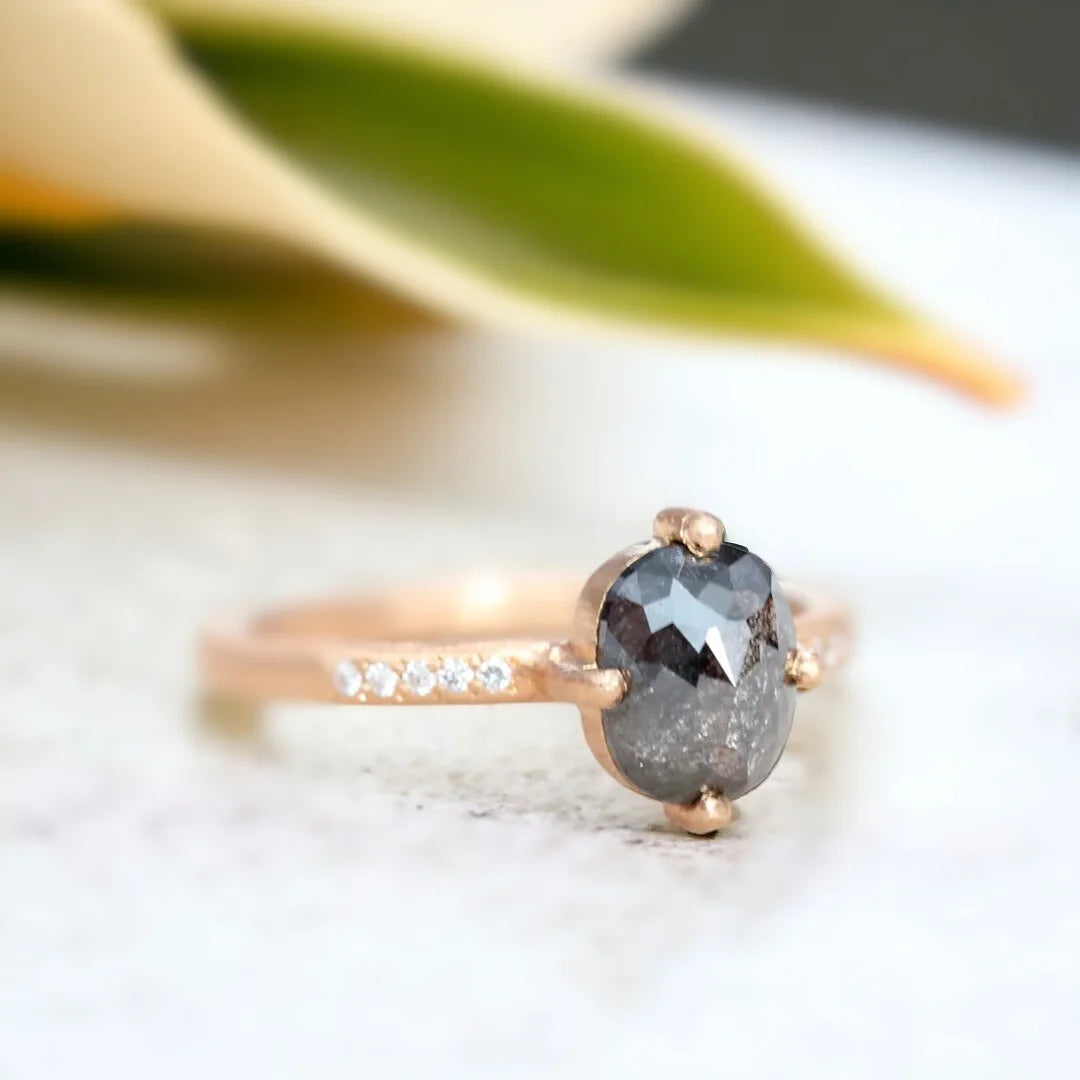 Rose Cushion Salt and Pepper Diamond Ring 1.70 CT featuring a rose cushion-cut salt-and-pepper diamond with round side diamonds, a straight shank band, hand-hewn ripple texture detailing, and an artisan crafted engagement ring design.