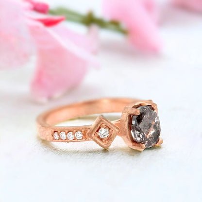 Rose Gold Salt and Pepper Diamond Ring with Oval Centre featuring an oval salt and pepper diamond centre stone in a rose gold setting with round side diamonds and a split-shank band design