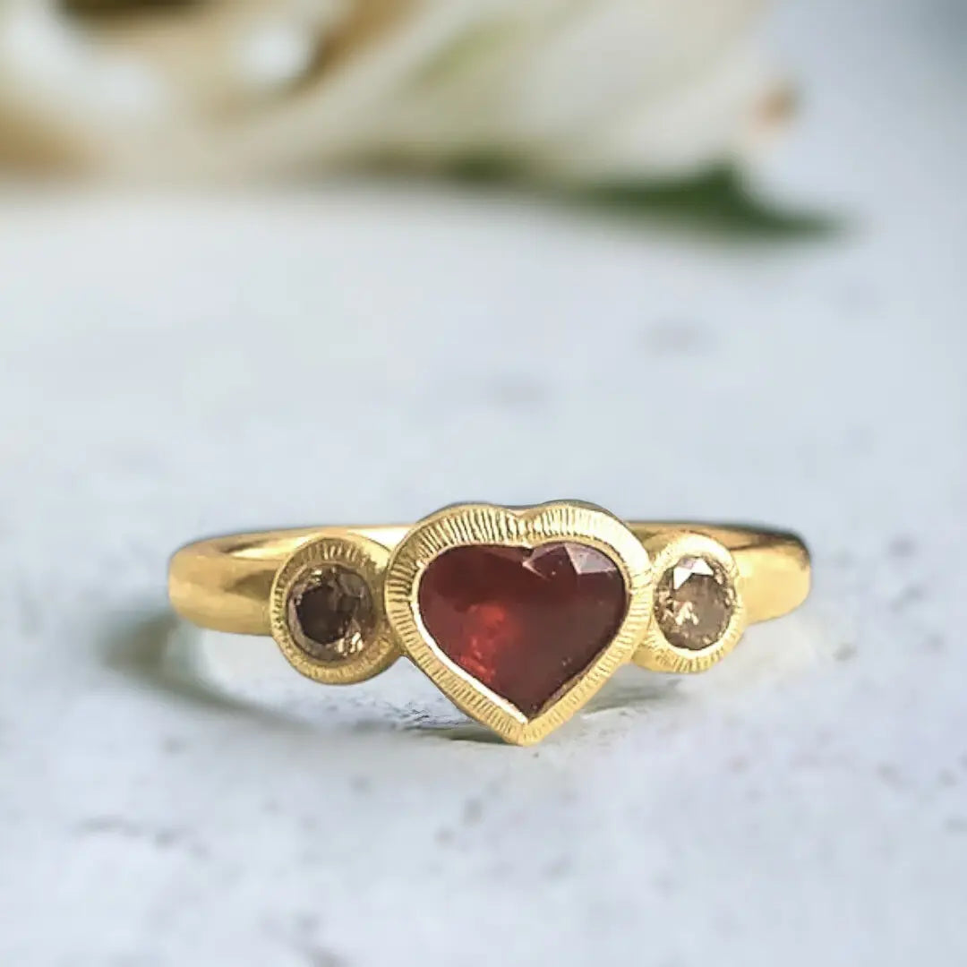 Ruby Heart Ring: Heart-shaped ruby ethical handmade design featuring a natural heart-shaped ruby centre stone with rich red colour, round brown diamond accents, and a slim straight band in a polished handmade setting.