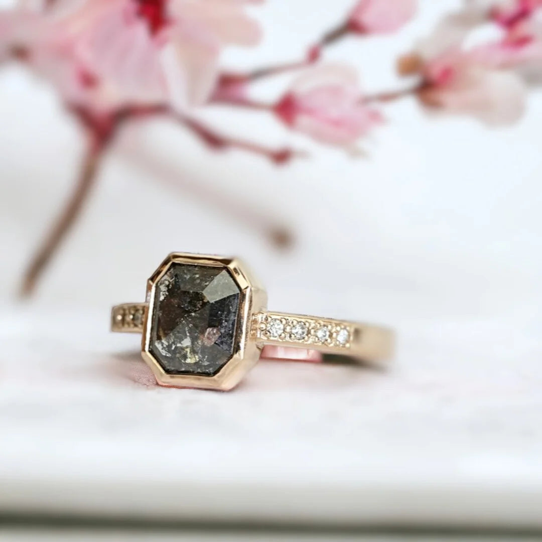 Salt and Pepper Diamond Anniversary Ring, Emerald Cut Milestone Ring featuring an emerald-cut natural salt-and-pepper diamond with round-cut side diamonds set in a slim straight band design with a minimalist and elegant milestone ring style