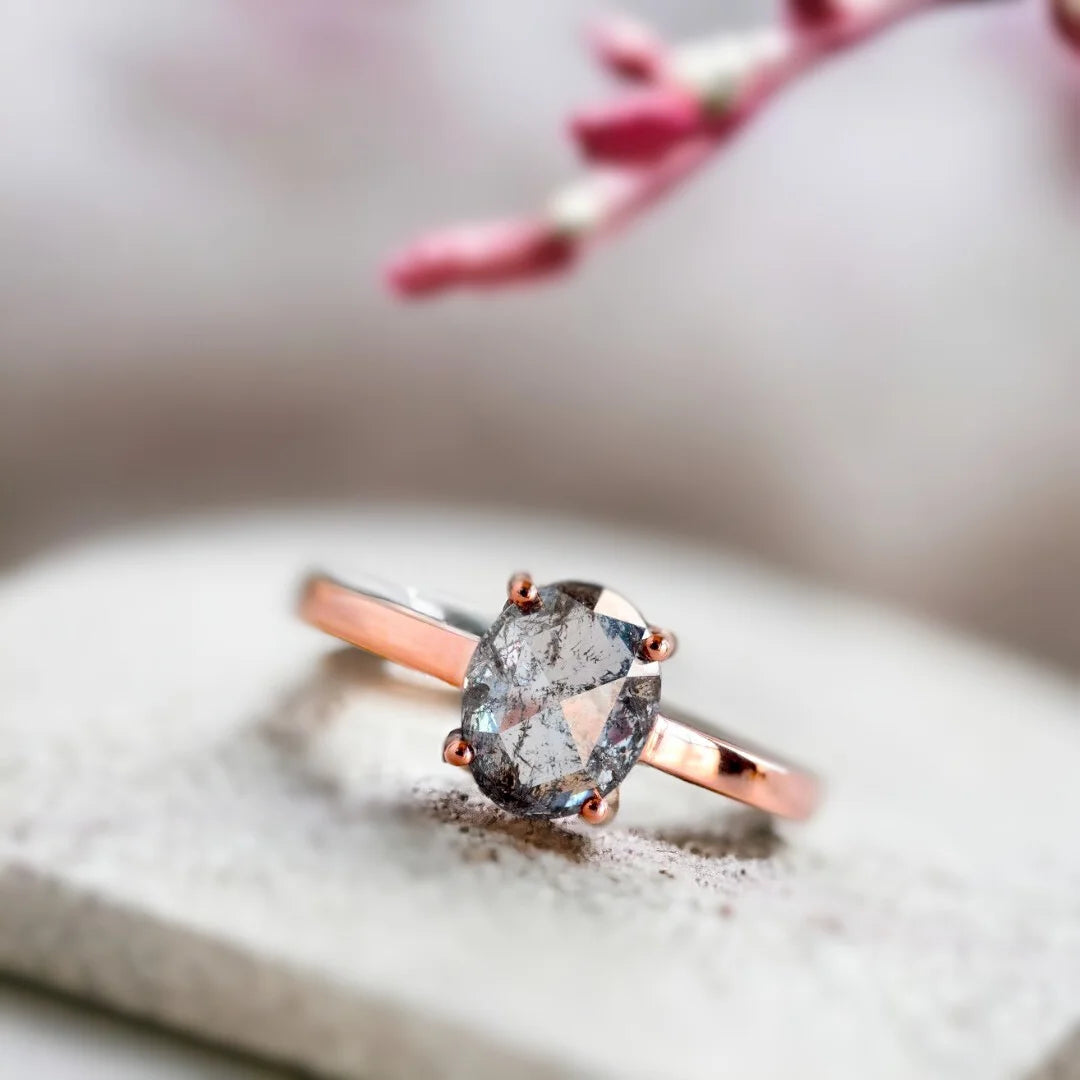 Salt and pepper diamond engagement ring set featuring a rose oval-cut center diamond in a rose gold straight shank bridal set with a coordinating wedding band and round accent diamonds in a handcrafted setting.